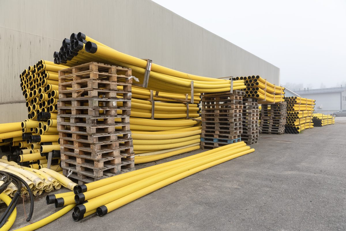 Keltaisia muoviputkia varastoituna päällekkäin UVR:n pihalla kuvattuna, vieressä kuormalavoja.