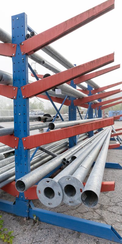 Metalliputkia varastoituna metallisiin sini-punaisiin telineisiin.