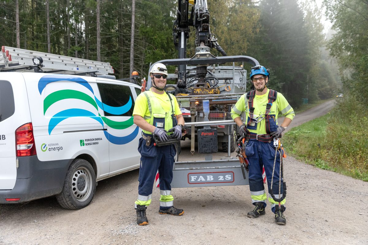 UVR:n kaksi ammatilaista henkilönostimen korin edessä työvarusteet päällä. Vasemalla huoltoauto.