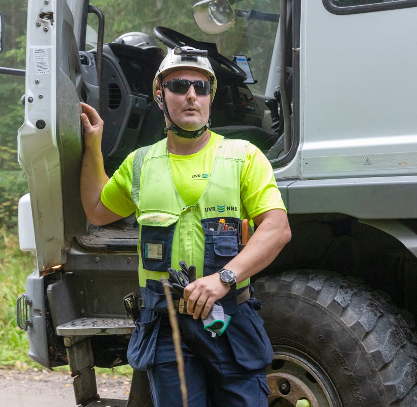 UVR:n työntekijä seisoo valkoisen kuorma-auton oven edessä, ovi on auki.